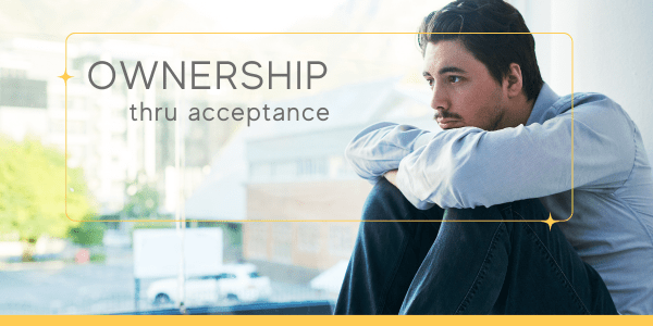 Middle-aged man sitting on the floor with knees pulled to his chest, chin resting on his knees, reflecting on difficult emotions as part of techniques for emotional regulation and accepting emotions.