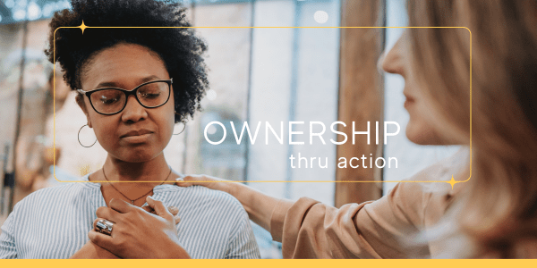 An African American middle-aged woman with glasses, eyes closed and hands on her heart, processing difficult emotions. She is supported by another woman, who stands by her side with a reassuring hand on her shoulder, offering comfort and solidarity during an emotional regulation technique.