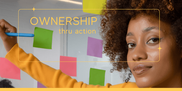 Confident young professional woman engaging in authentic living exercises by writing on a glass wall with colorful sticky notes, demonstrating ownership thru action in a modern office setting.