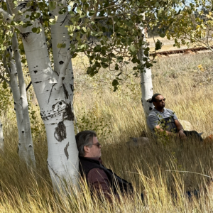 Two men sitting under Aspen trees at a Flagstaff forest corporate team building event